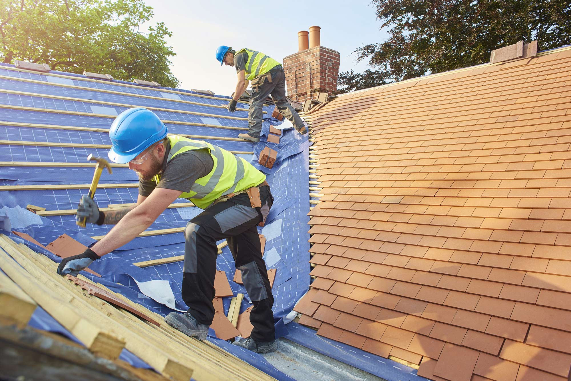 Roofer nailing on shingles to residential roof